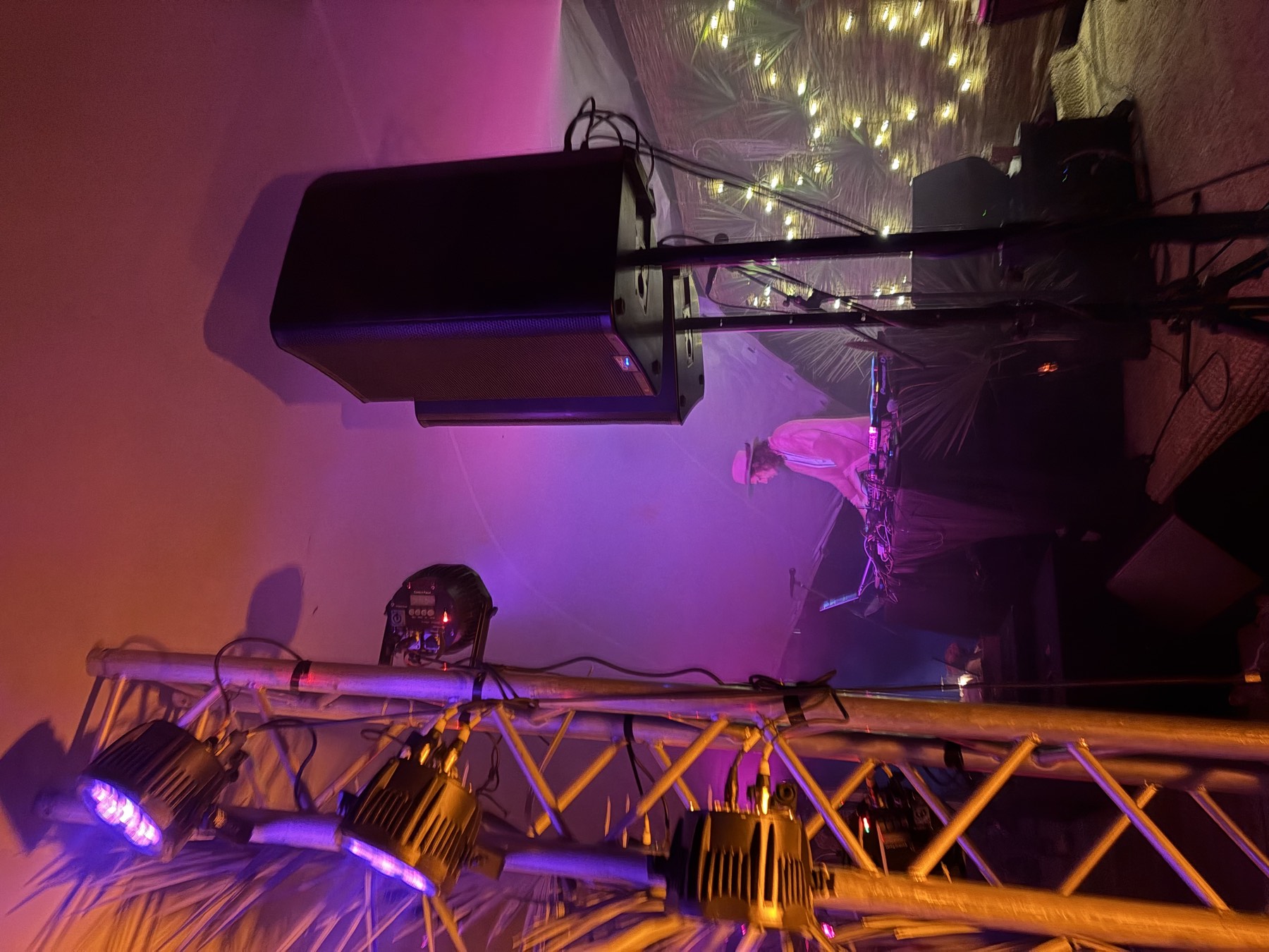 Powered QSC speaker on a stand beside a lighting truss